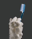 conceptual still life image of toothbrush and refreshment glass full of sugar cubes in dental care and oral hygiene conce