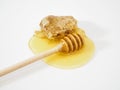 Wooden ladle for honey on a drop of honey and honeycomb on a white background close up