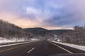 Isolated empty highway surrounded by wintery snow scene under a colorful stormy sky Royalty Free Stock Photo