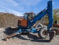 Isolated excavator parked in a rural area of blue and orange color