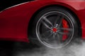 Isolated generic red sport car with detail on wheel with red breaks drifting and smoking on a dark background Royalty Free Stock Photo