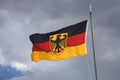 isolated German flag with coat of arms in front of dark grey clouds