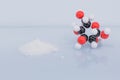 Isolated glucose molecule made by molecular model next to a little heap of white sugar.