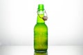 Isolated green bottle of Grolsch beer on a white background lighted from behind