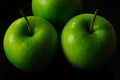 isolated green apples in closeup view with long stems. black background. freshness and healthy eating Royalty Free Stock Photo