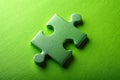 Isolated Green Jigsaw Piece Symbolizing Unity and Connection on a Vibrant Green Background Royalty Free Stock Photo