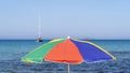 Isolated green, red, blue and yellow beach umbrella. Blue sky. Relaxing context. Summer holidays at the sea Royalty Free Stock Photo