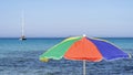 Isolated green, red, blue and yellow beach umbrella. Blue sky. Relaxing context. Summer holidays at the sea Royalty Free Stock Photo