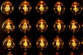 Isolated group of yellow gold shining retro classical light bulbs in rows with glowing filaments and black background