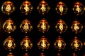 Isolated group of yellow gold shining retro classical light bulbs in rows with glowing filaments and black background