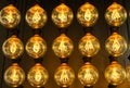 Isolated group of yellow gold shining retro classical light bulbs in rows with glowing filaments and black background