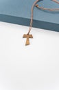 isolated hand made wooden tau cross pendant on a blue box