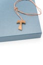 isolated hand made wooden tau cross pendant on a blue box