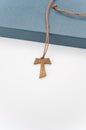 isolated hand made wooden tau cross pendant on a blue box