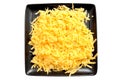 Isolated image of grated hard cheese on a black square plate.