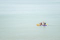 Isolated kayak paddlers on a big, calm sea.