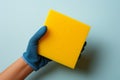 Isolated latex gloved hand wields a dishwashing sponge for spotless, clean dishes