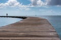 An isolated man walking on a curved pier. some sailing boats on he sea Royalty Free Stock Photo
