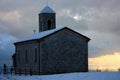 Isolated mountain church built in stone with a steeple all covered by the cold white winter snow Royalty Free Stock Photo