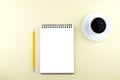 Isolated notepad with a pencil and black coffee on a yellow background.