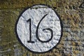 Isolated number 16 painted in a circle on a stone wall