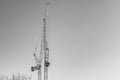 Isolated pair of large construction cranes seen against a clear, winter sky.