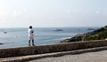 Isolated person walking on top a small stone wall and the Mediterranean Sea at the background in the old citadel of Ibiza