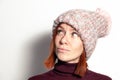 Isolated portrait of beautiful young redhead girl in purple sweater and pink knitted hat with pompon dressed sideways smiling