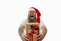 Isolated portrait on a white background of an overweigh laughing man with tattooed arms in Santa hat presenting Christmas gifts