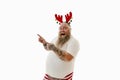 Isolated portrait on a white background of an overweigh man with tattooed arms wearing a hoop with antlers on the head gesturing