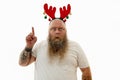 Isolated portrait on a white background of an overweigh corpulent bearded man with tattooed arms wearing a hoop with antlers on