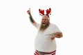 Isolated portrait on a white background of an overweigh man with tattooed arms wearing a hoop with antlers on the head putting one