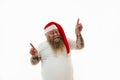 Isolated portrait of an overweigh smiling bearded man in Santa hat with tattooed arms on the head pointing his fingers up