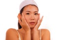 Young beautiful and happy Asian Korean woman applying skincare wrinkle prevention treatment or aging beauty product on her face in