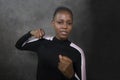 Isolated portrait of young cool and confident black afro American woman in fighting stance looking defiant rising her fist Royalty Free Stock Photo