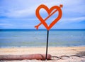 Isolated post signal with red love heart and arrow at beach on a blue sea and sky background in Valentines day and romance concept Royalty Free Stock Photo