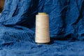Isolated, pristine spool of white thread set against a blue background Royalty Free Stock Photo