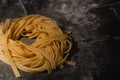 Isolated raw pasta on a black background with a place for text. Traditional Italian pasta, noodles, tagliatelle. Top view. Copy