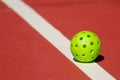 Isolated shot of a standard yellow Pickleball ball set on a tennis court