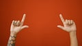 Isolated shot of tattooed adult man\'s hands, his finger pointing up over the blank space in an vivacious red background Royalty Free Stock Photo