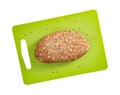 Isolated sliced bread with seeds and flakes on green rectangular cutting board on white background.