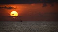 Isolated small fishing boat and the golden sunset, the fishing boat sails as the sun sets behind the clouds and the horizon. Royalty Free Stock Photo