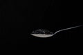 Isolated spoon full of dryed sesame seeds in a black background