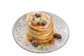 Isolated stack of hot pancakes with nuts, dried fruits and caramel syrup.