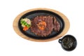 Isolated top view of medium rare wagyu steak topping with mince carrot on hot plate and wooden plate served with potato salad. Royalty Free Stock Photo