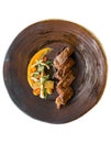 Isolated top view of roasted medium rare wagyu beef served with sour sauce with roasted baby vegetables on stone plate