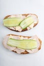 Isolated vertical close up top view shot of a pair of two white bread turkey ham and cheese sandwiches with a slice of cucumber on Royalty Free Stock Photo