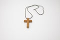 Closeup and isolated view of a small wooden cross on a string Royalty Free Stock Photo