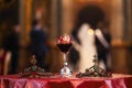 Isolated wedding crowns and blurred glass of vine in background. Orthodox church wedding accessories