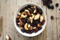 Isolated little white bowl of mixed nuts and dried fruits on the rustic background Royalty Free Stock Photo